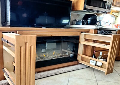 tv lift with built in ffire place, custom built pull outs on the side for bottle storage