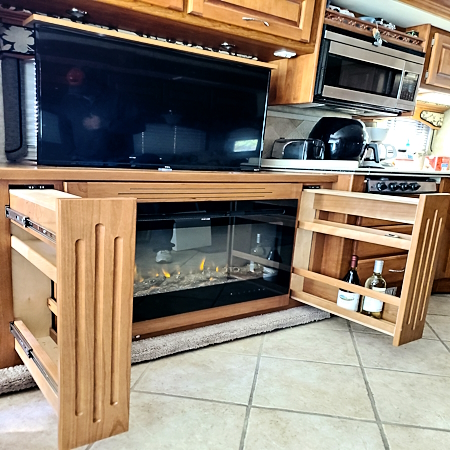 tv lift with built in ffire place, custom built pull outs on the side for bottle storage